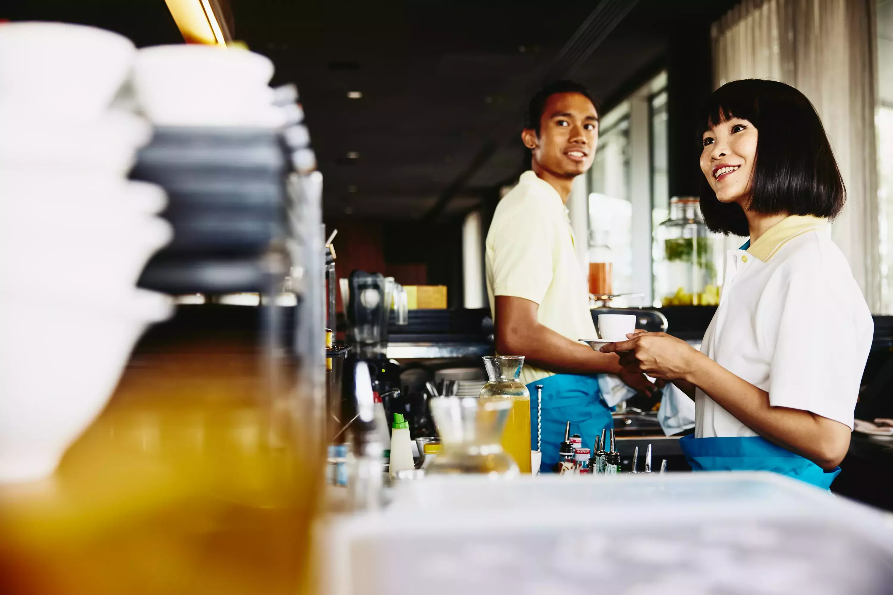 male and female bar tending. Womale holding acoffee cup.
