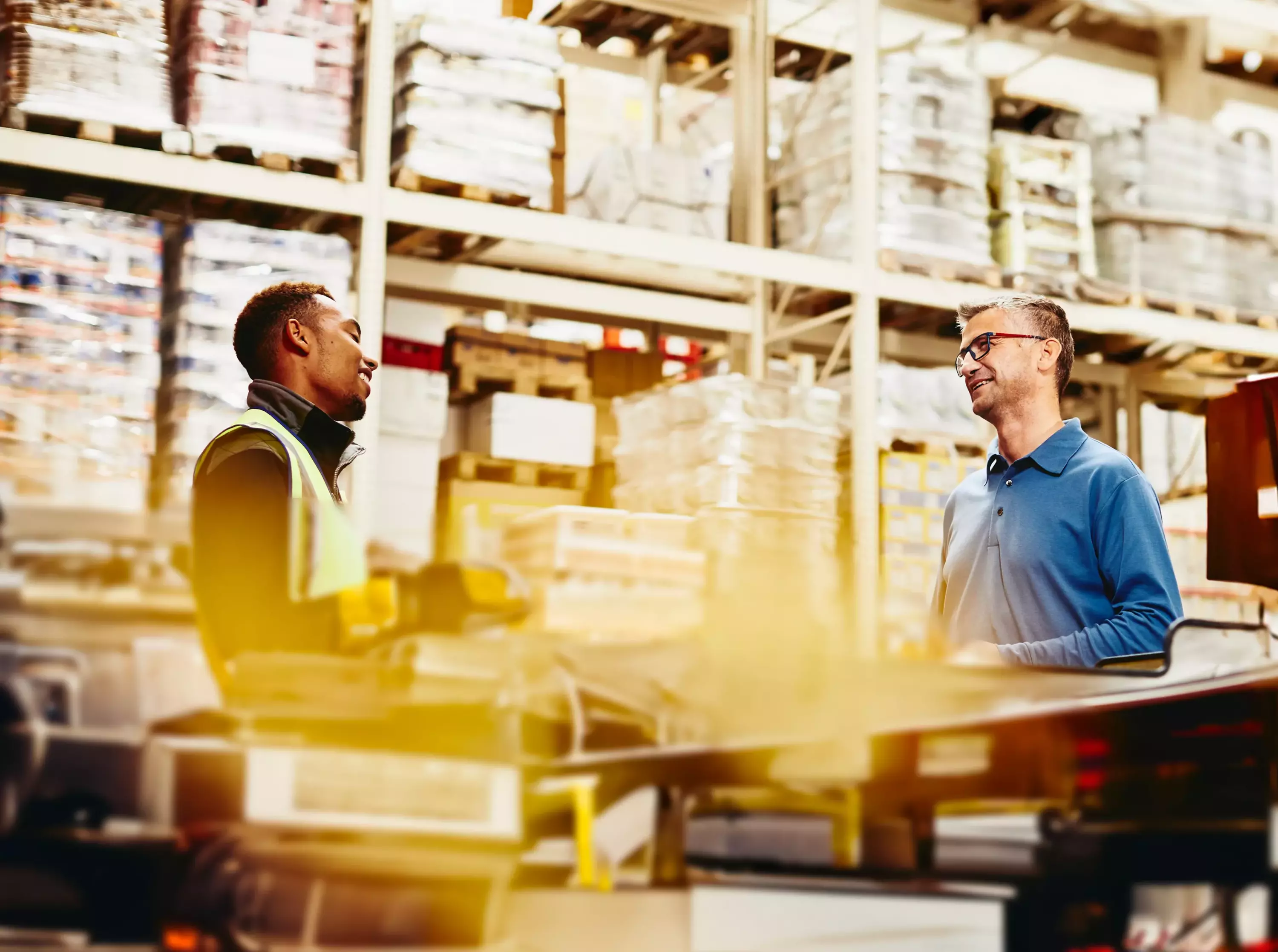 Two male working/having a conversation in a warehouse
