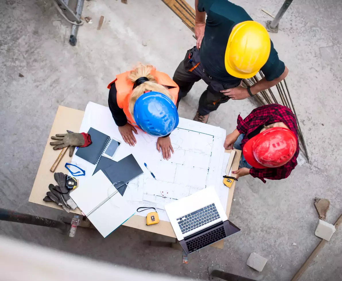 Three architects examining the blueprints on construction site