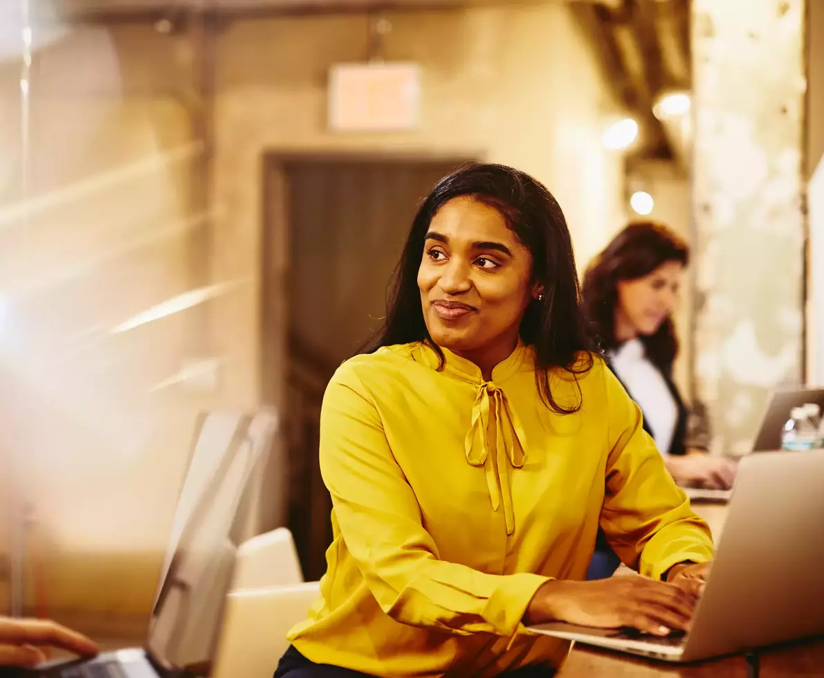 Two smiling female working on their laptop.
