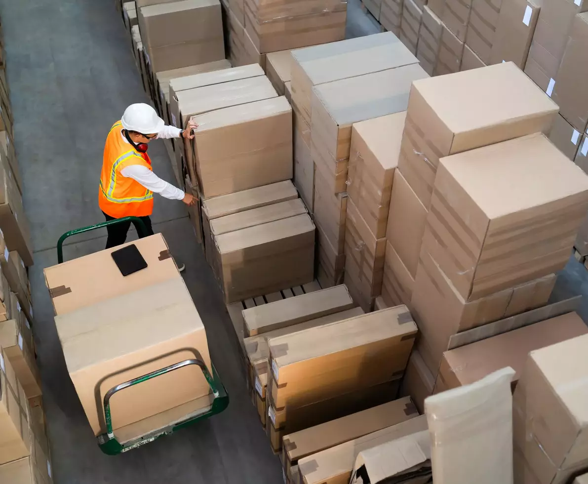 Aerial view of a logistic warehouse worker delivering boxes on a trolley