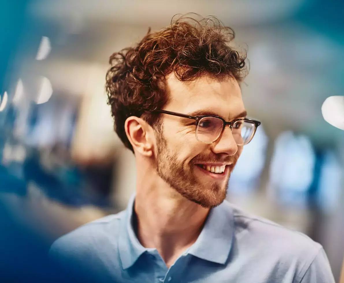 Male with glasses smiling and looking to the side
