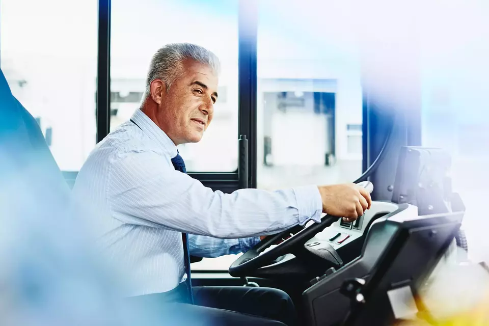 Male bus driver behind the steering wheel on the bus
