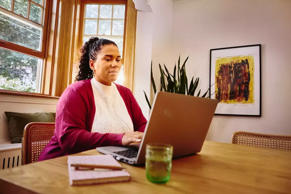 Female working on laptop on a table at home
