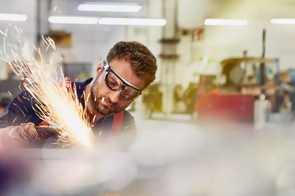 male wearing safety glasses, grinding metal
