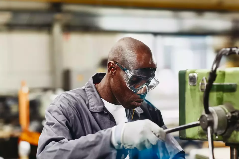 Factory worker operating a column drill. 
